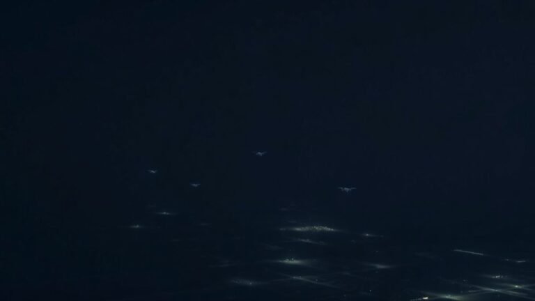 Drones flying over a military base at night.