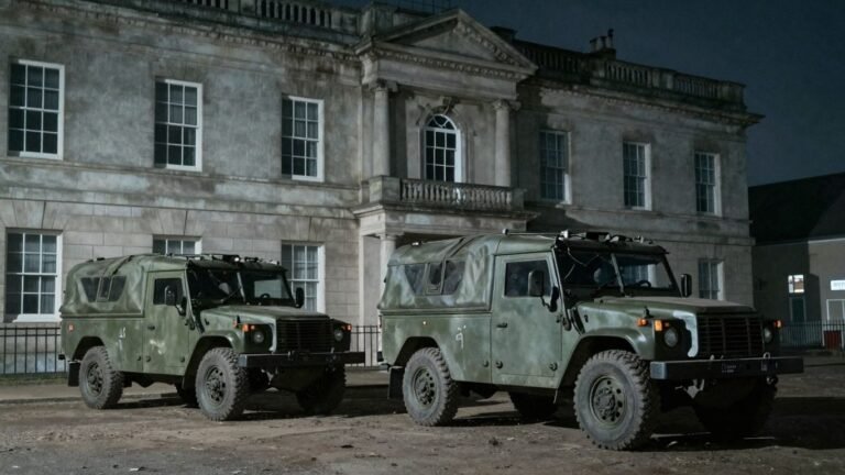 British Army vehicle near a shadowy, imposing building.