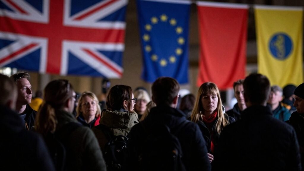 Migrants at UK visa processing center with flags.