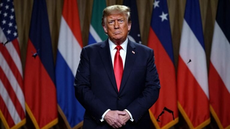 Trump stands resolutely before torn global flags.